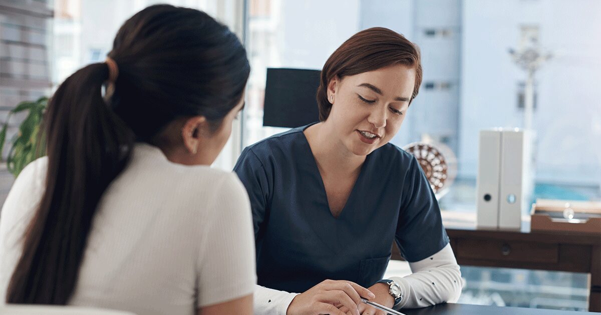 Healthcare professional explaining how pregnancy tests work while meeting with a woman during a pregnancy consultation.